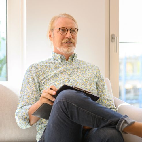 Patient sitzt im Wartezimmer mit einem Bogen zum ausfüllen - quadratisches Format