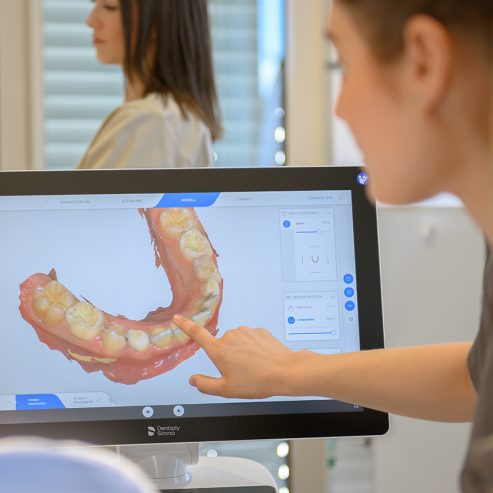 Ärztin zeigt auf einen Monitor mit 3D Modell vom Gebiss eines Patienten - quadratisches Format